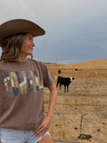 Brown T-shirt, words say cowgirl in oldtime  looking gingam , lace, deniem writing. Patch working inspried letters